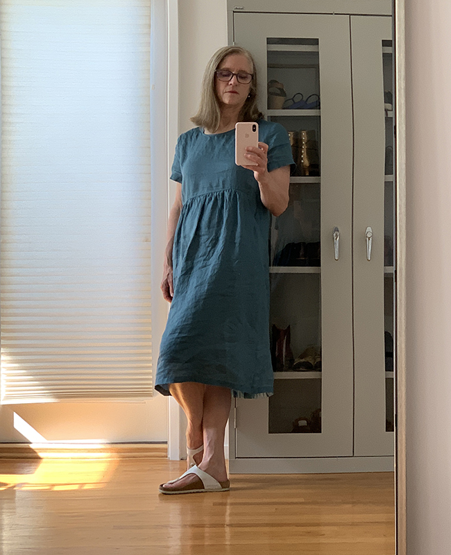 Woman leaning on cupboard in blue dress