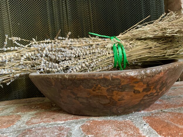 A bunch of lavender tied with green raffia in front of a fireplace