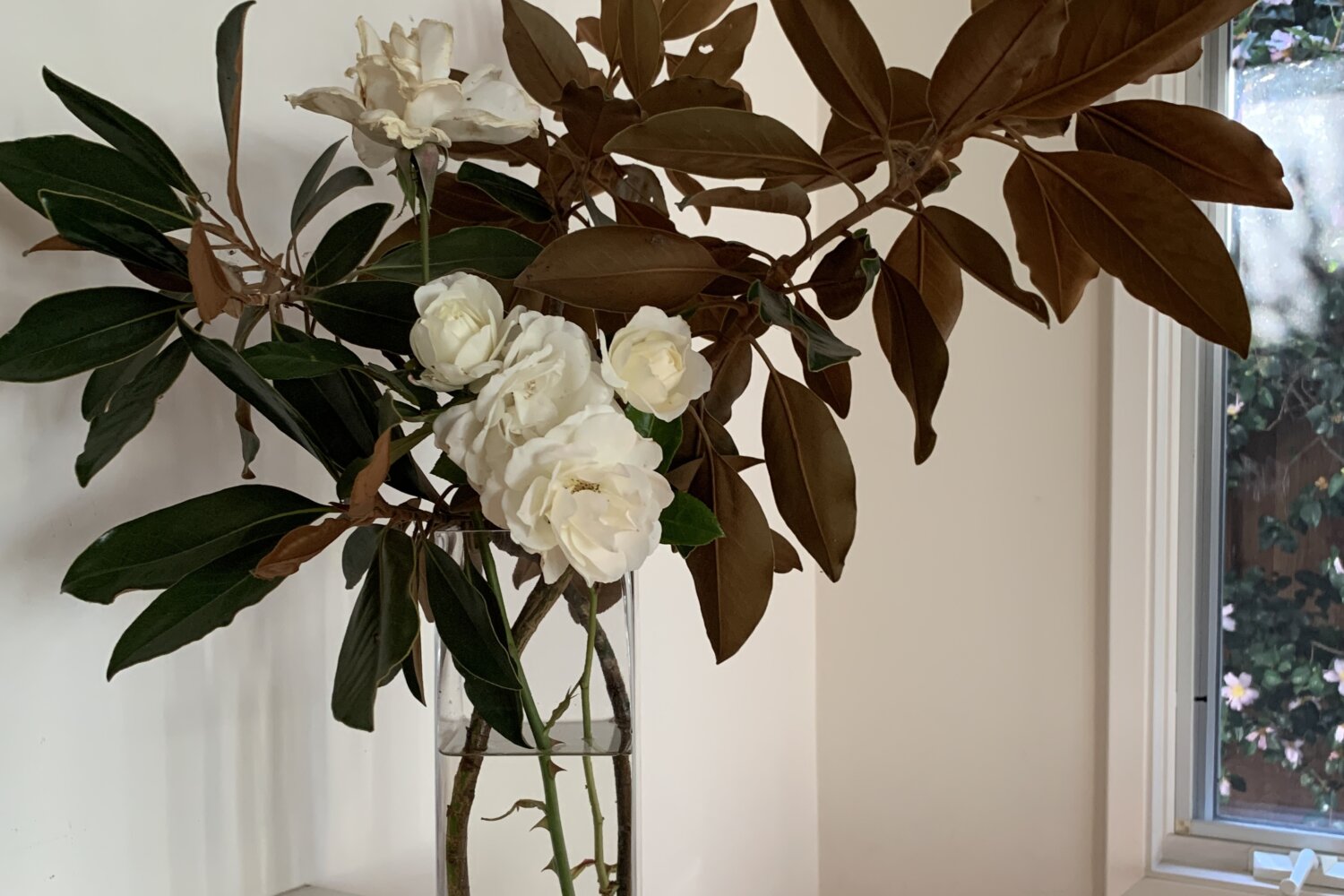 An arrangement of magnolia branches and white roses