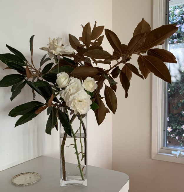 An arrangement of magnolia branches and white roses