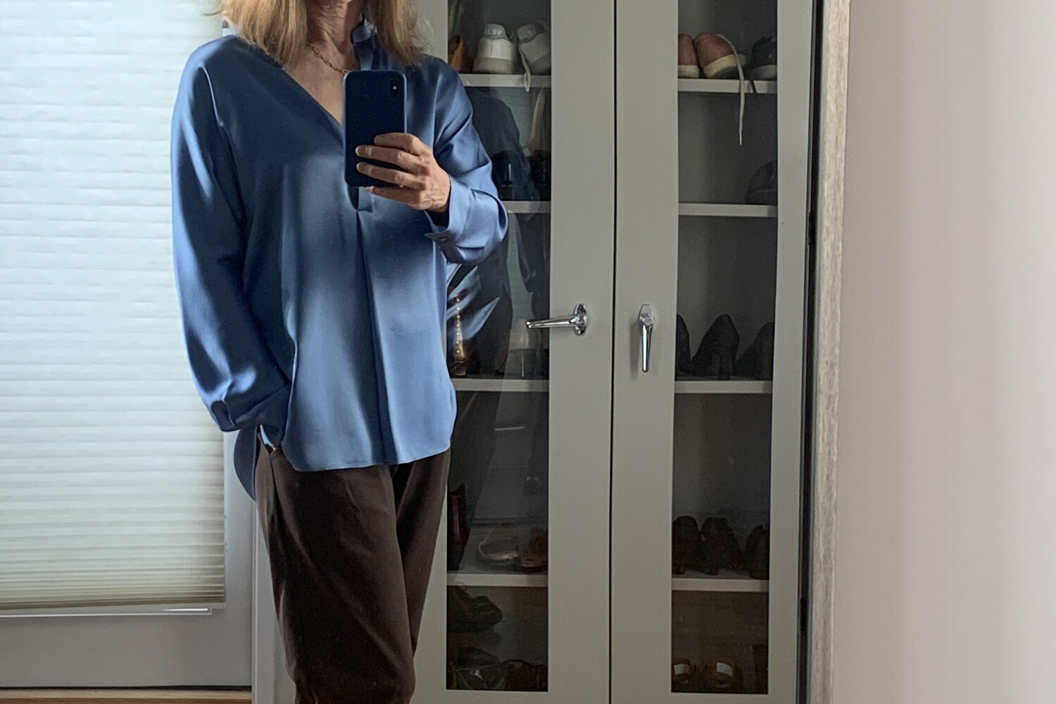 Woman in her 60s wearing a blue silk tunic and brown Eileen Fisher Carrot pants