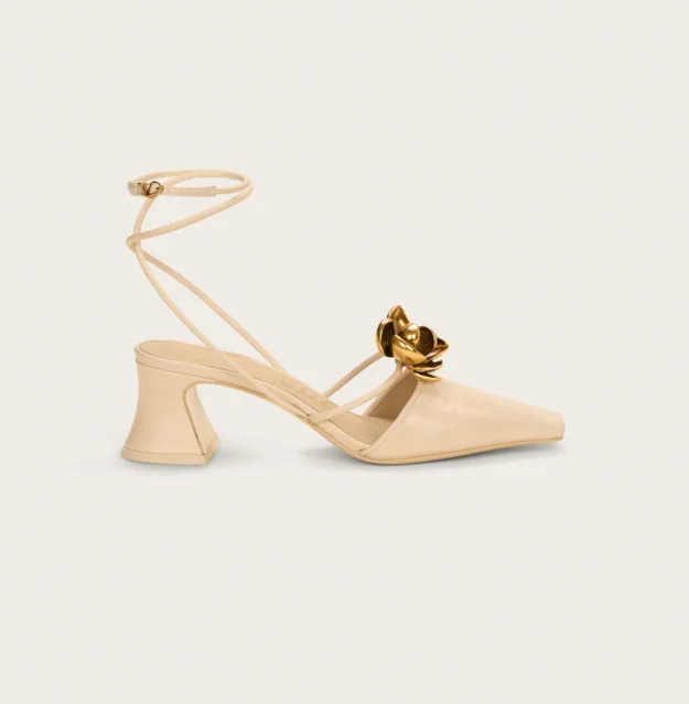 Slingback by Cult Gaia, with an architectural heel, crossed ankle straps, and a brass flower ornament at the toe.