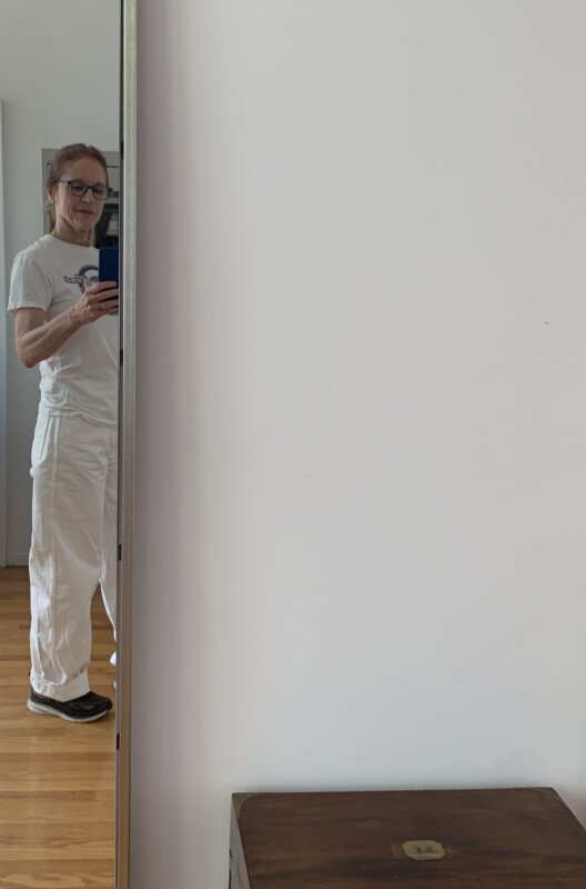 Older woman in white jeans, sneakers, and a graphic tee