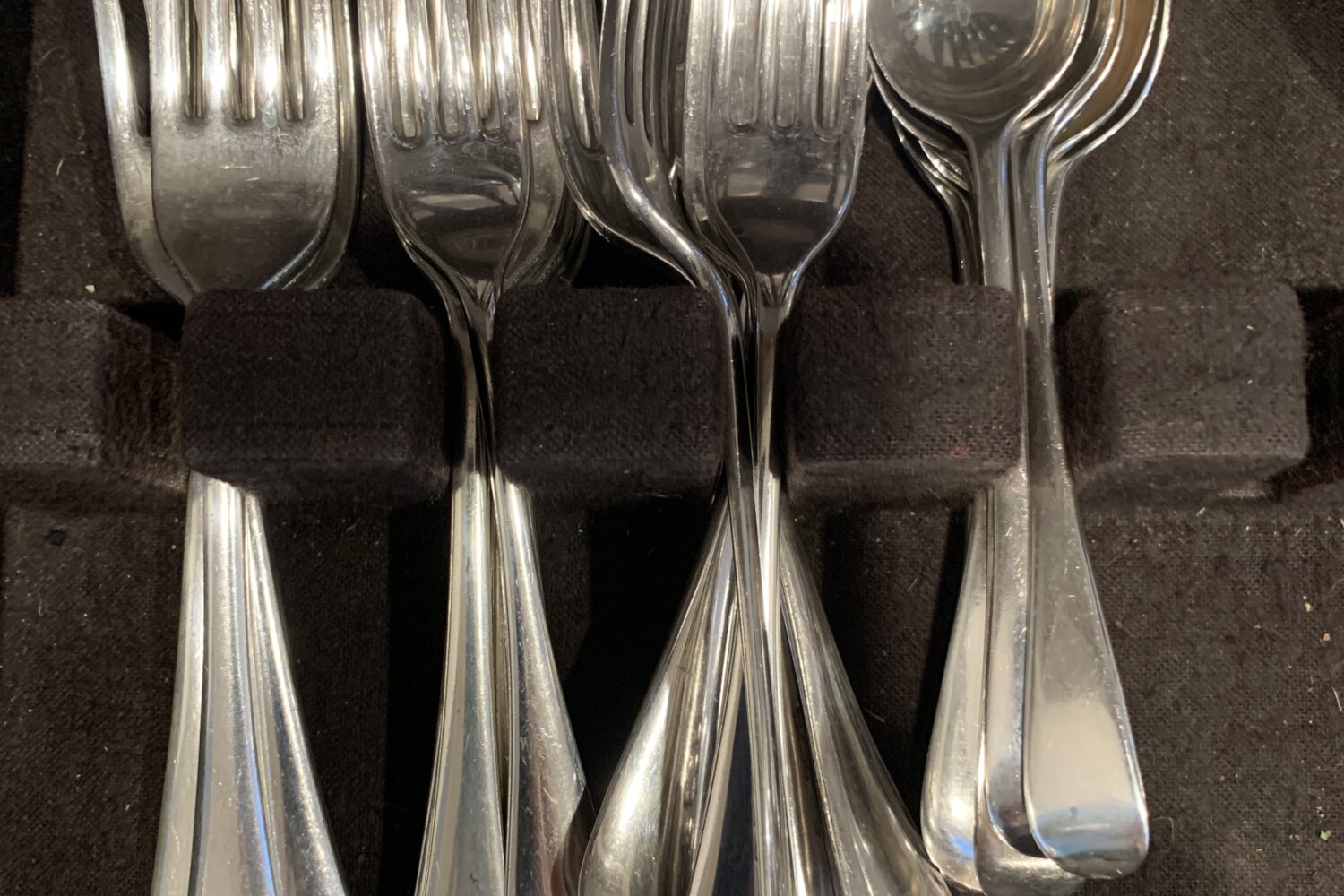Polished silver forks and spoons in an open box.