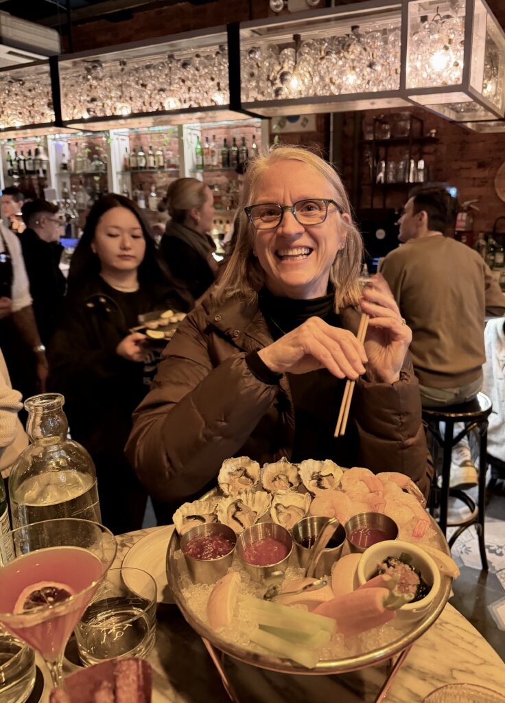 Woman in Korean restaurant in NYC holding chopsticks in front of a plate of oysters