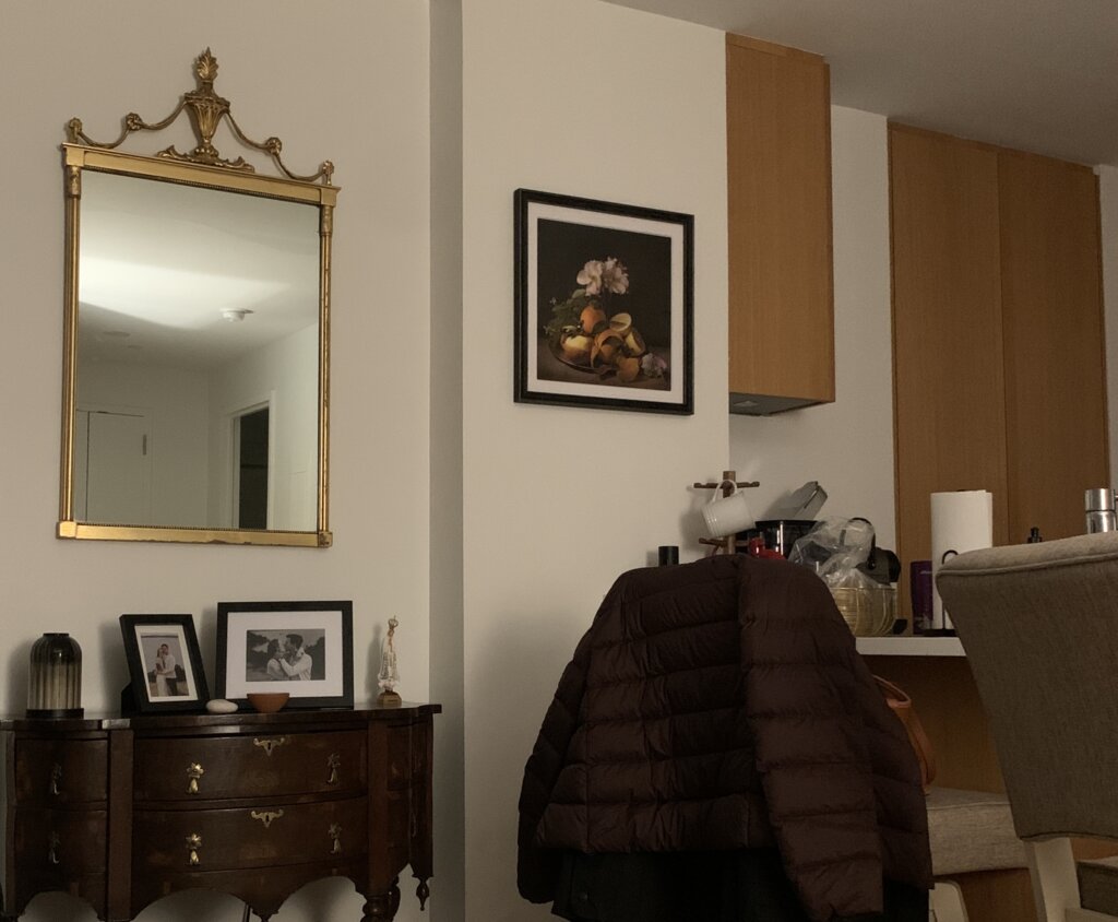 An apartment wall with a gold-framed antique mirror and a photo by the artist Brigitte Carnochan