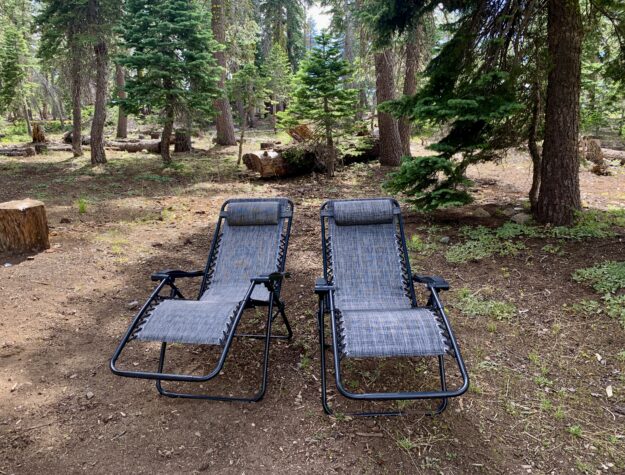 Two portable lounge chairs, set up on a campsite in the High Sierra